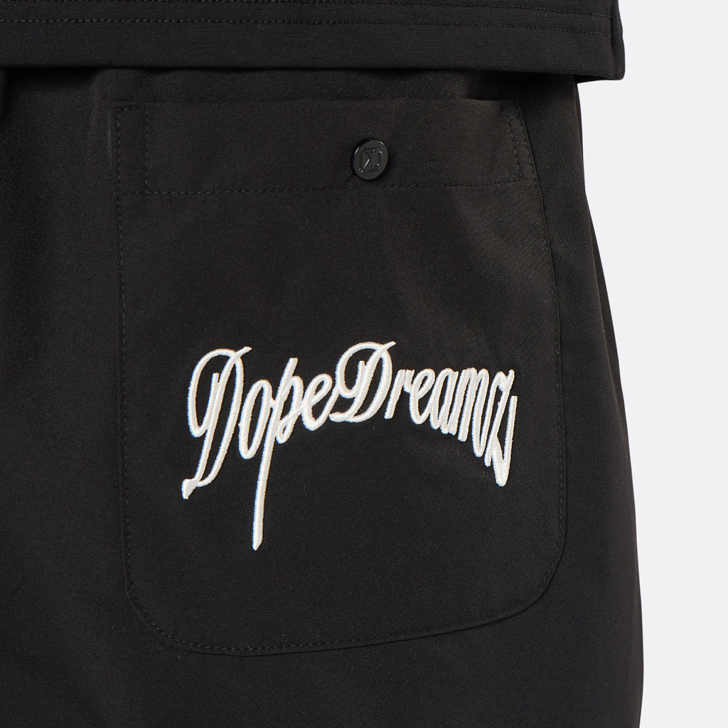 Close-up of the DopeDreamz Interlude Noir black premium shorts featuring the white embroidered DopeDreamz back pocket graphic and tonal DDZ metal button.