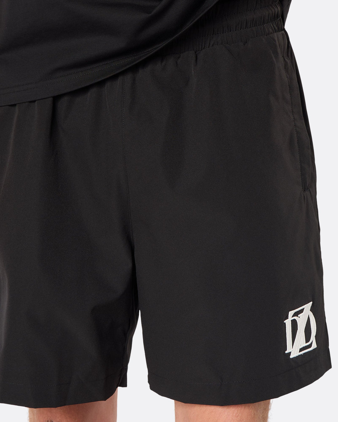 Close-up of the DopeDreamz Interlude Noir black premium shorts featuring the white embroidered DDZ logo.