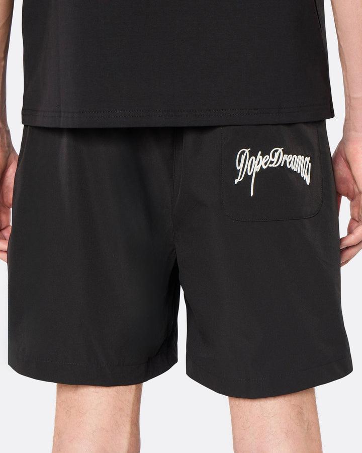 Close-up back view of the DopeDreamz Interlude Noir black premium shorts featuring the white embroidered DopeDreamz back pocket graphic.