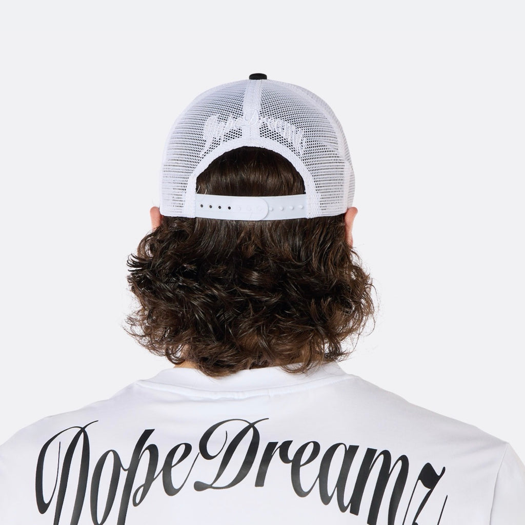 Close-up back view of a male model wearing the DopeDreamz Interlude Noir black and white trucker cap with white embroidered DopeDreamz rear logo.