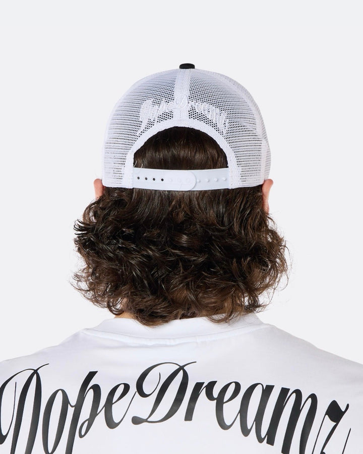 Close-up back view of a male model wearing the DopeDreamz Interlude Noir black and white trucker cap with white embroidered DopeDreamz rear logo.