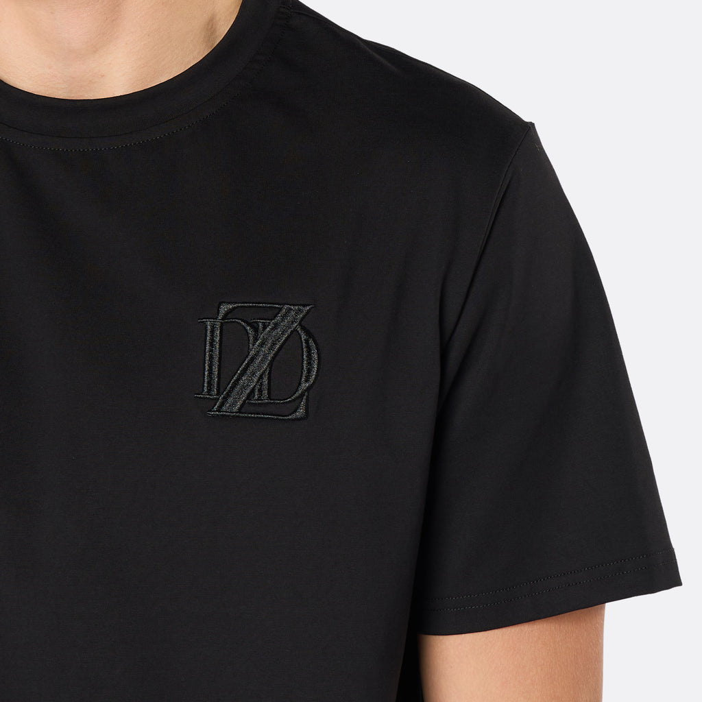 Close-up of the DopeDreamz Interlude Noir black premium T-shirt featuring the tonal black embroidered DDZ chest logo.