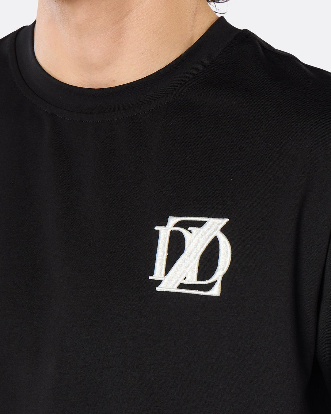 Close-up of the DopeDreamz Interlude Noir black premium T-shirt featuring the white embroidered DDZ chest logo.
