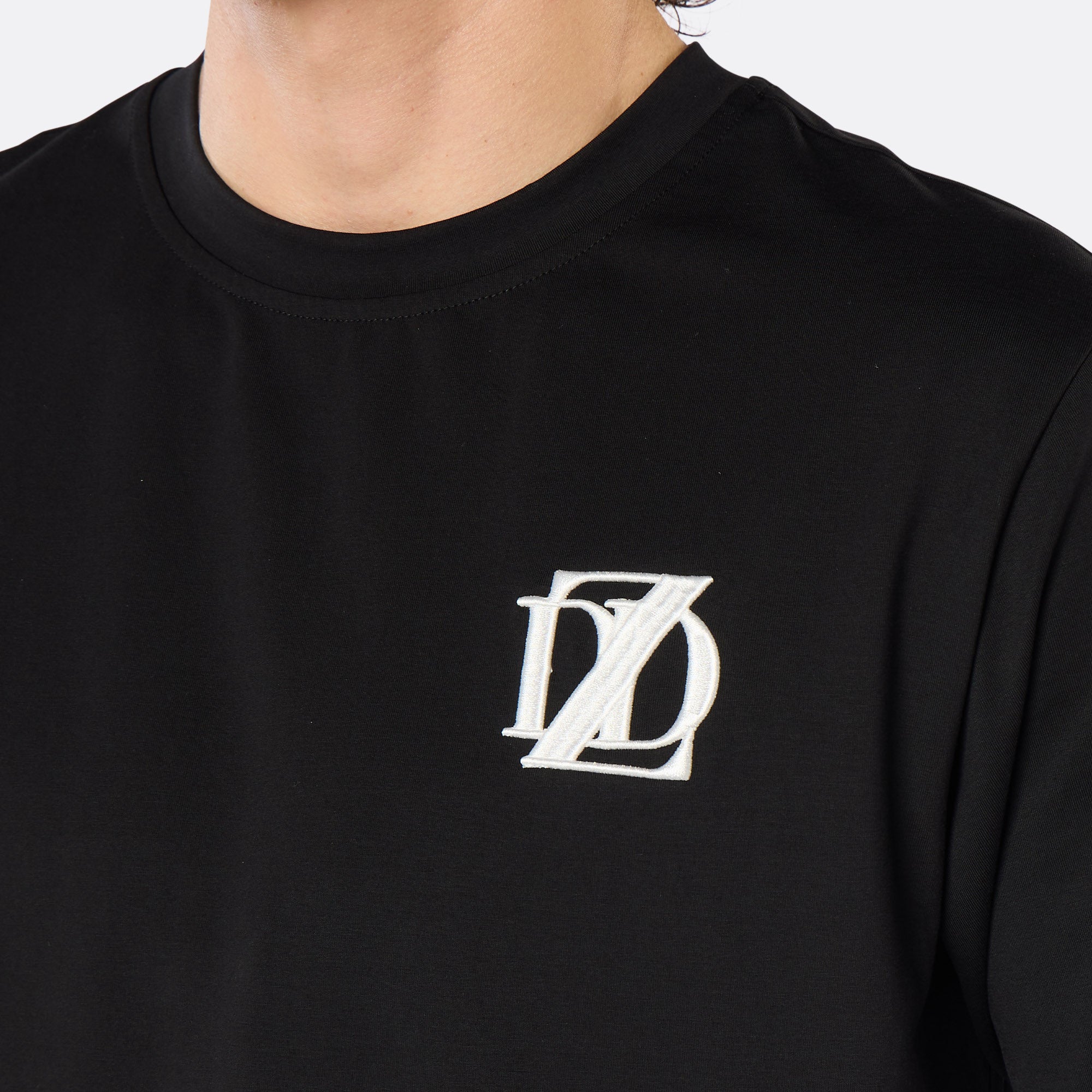 Close-up of the DopeDreamz Interlude Noir black premium T-shirt featuring the white embroidered DDZ chest logo.