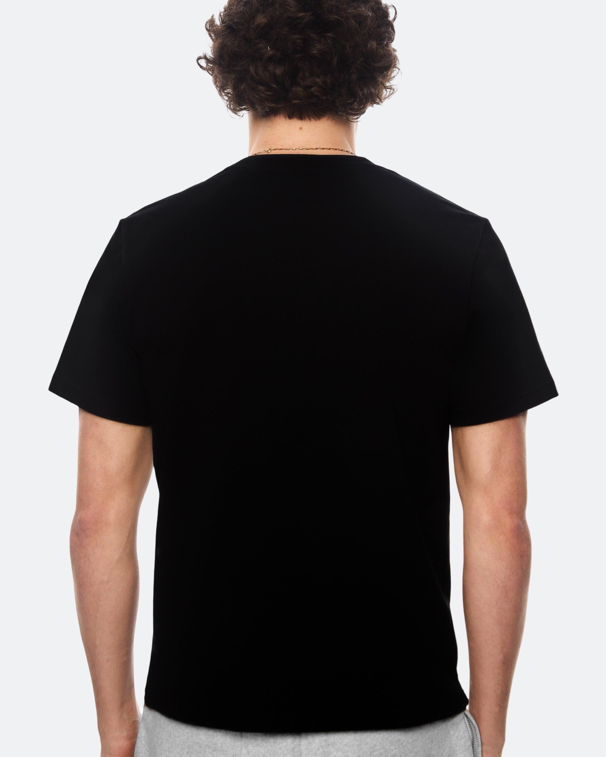 Back view of model wearing black DopeDreamz t-shirt on light background
