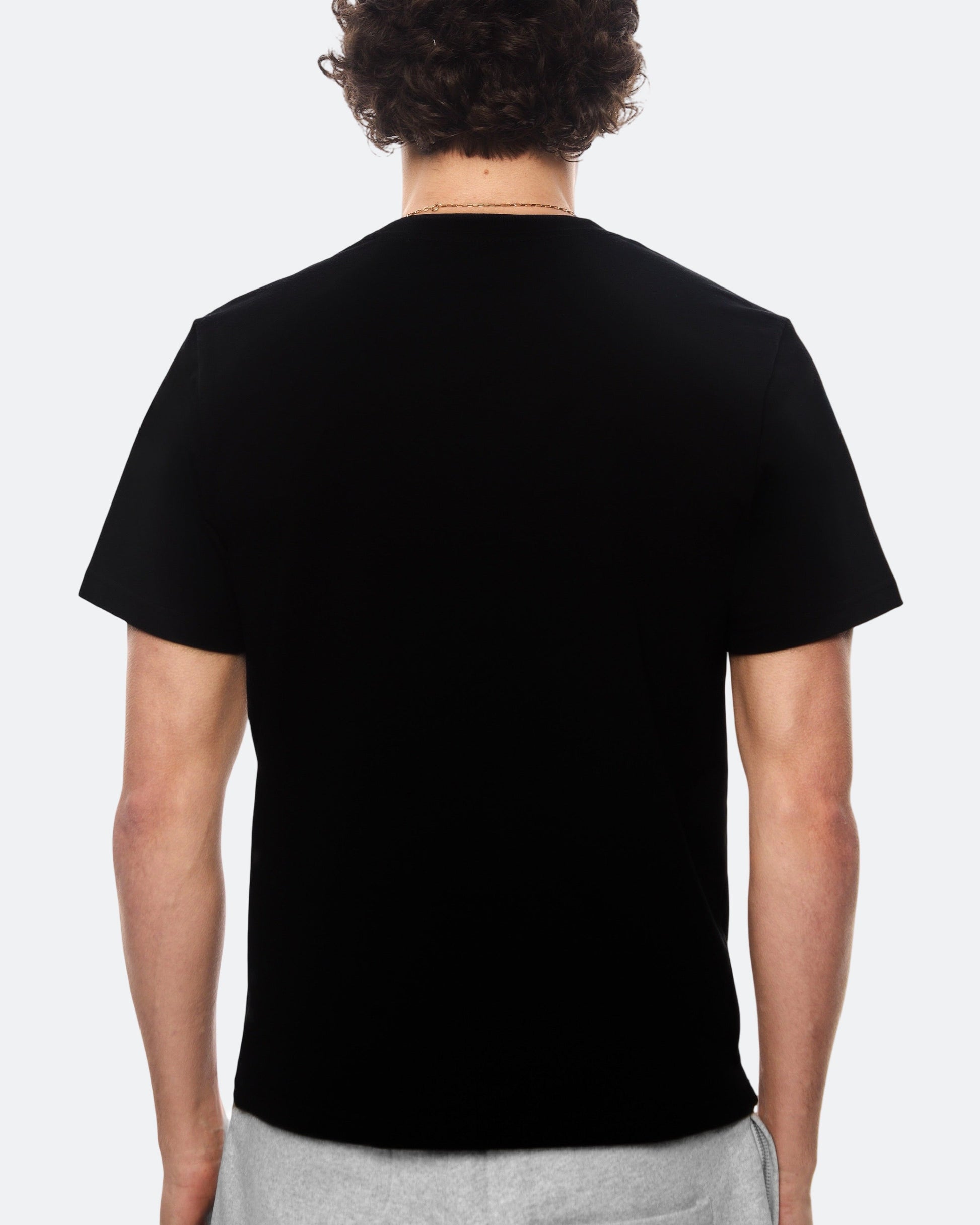 Back view of model wearing black DopeDreamz t-shirt on light background
