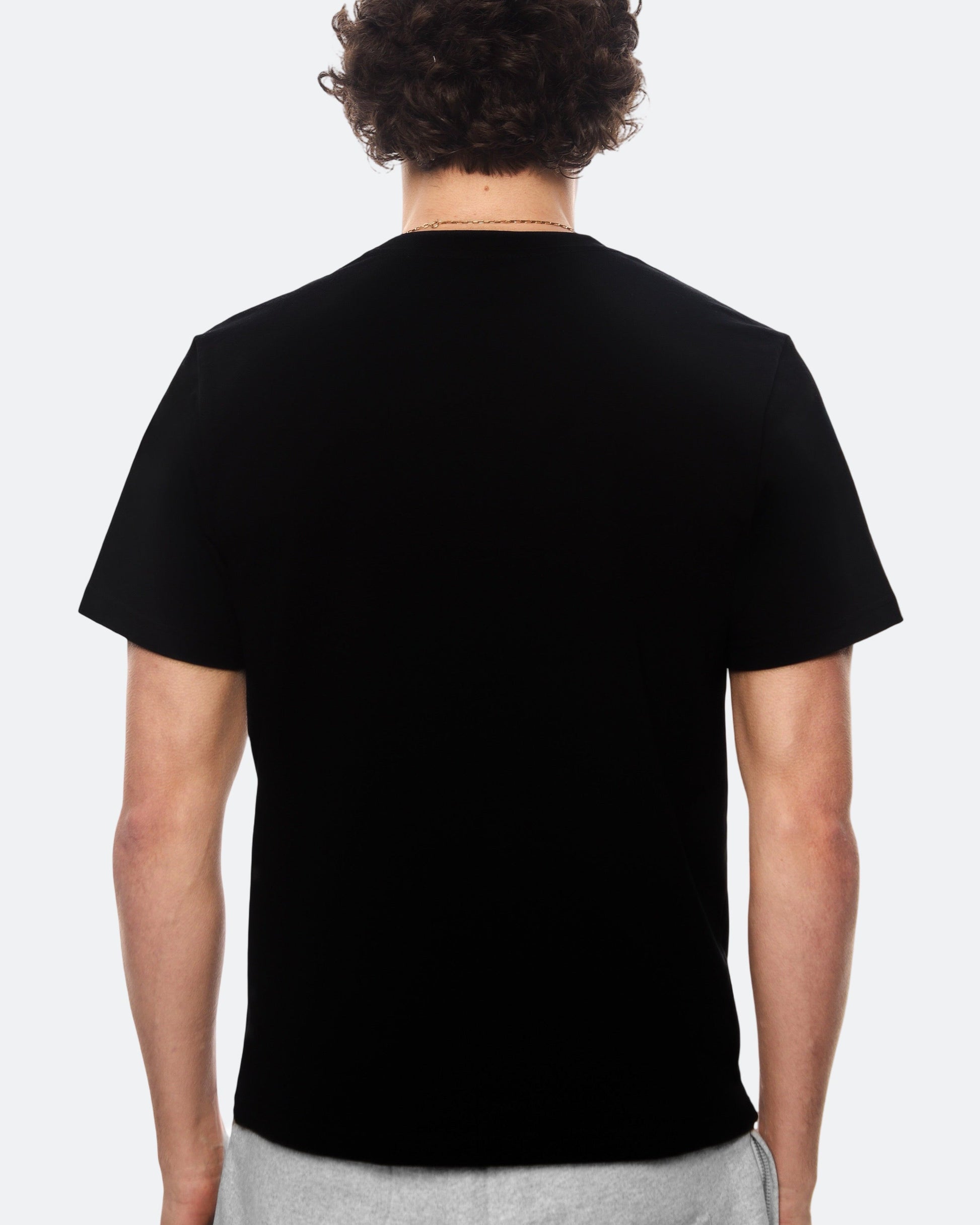 Back view of a model wearing a black t-shirt against a white background
