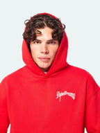 Model wearing red DopeDreamz hoodie with white embroidered chest logo, close up detail face shot view on white background
