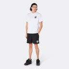 Male model wearing the DopeDreamz Interlude Noir white premium T-shirt with black DDZ chest logo and black shorts with white DDZ logo, three-quarter side view. 