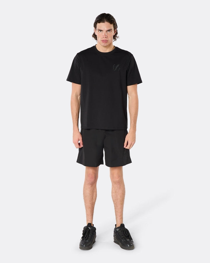 Male model wearing the DopeDreamz Interlude Noir black premium T-shirt with tonal black DDZ chest logo and black shorts with tonal black DDZ logo, front view.