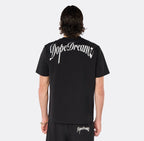 Male model wearing the DopeDreamz Interlude Noir black premium T-shirt with white DopeDreamz back graphic and black shorts with white DopeDreamz logo, back view.