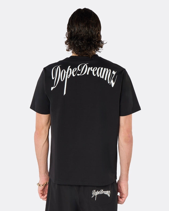 Male model wearing the DopeDreamz Interlude Noir black premium T-shirt with white DopeDreamz back graphic and black shorts with white DopeDreamz logo, back view.
