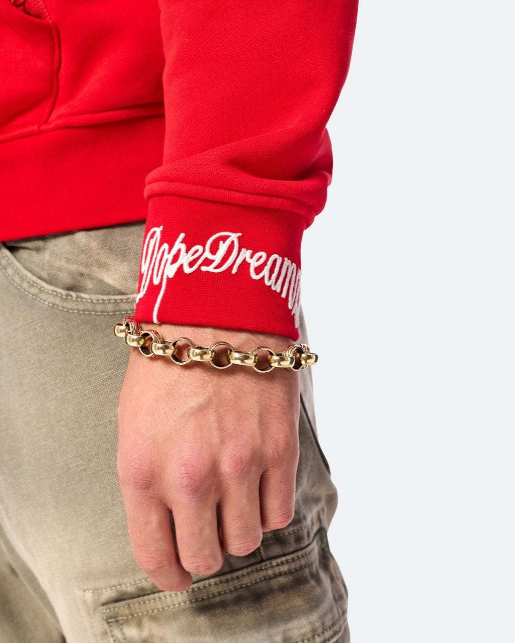 Close-up of white embroidered DopeDreamz logo on red hoodie sleeve cuff
