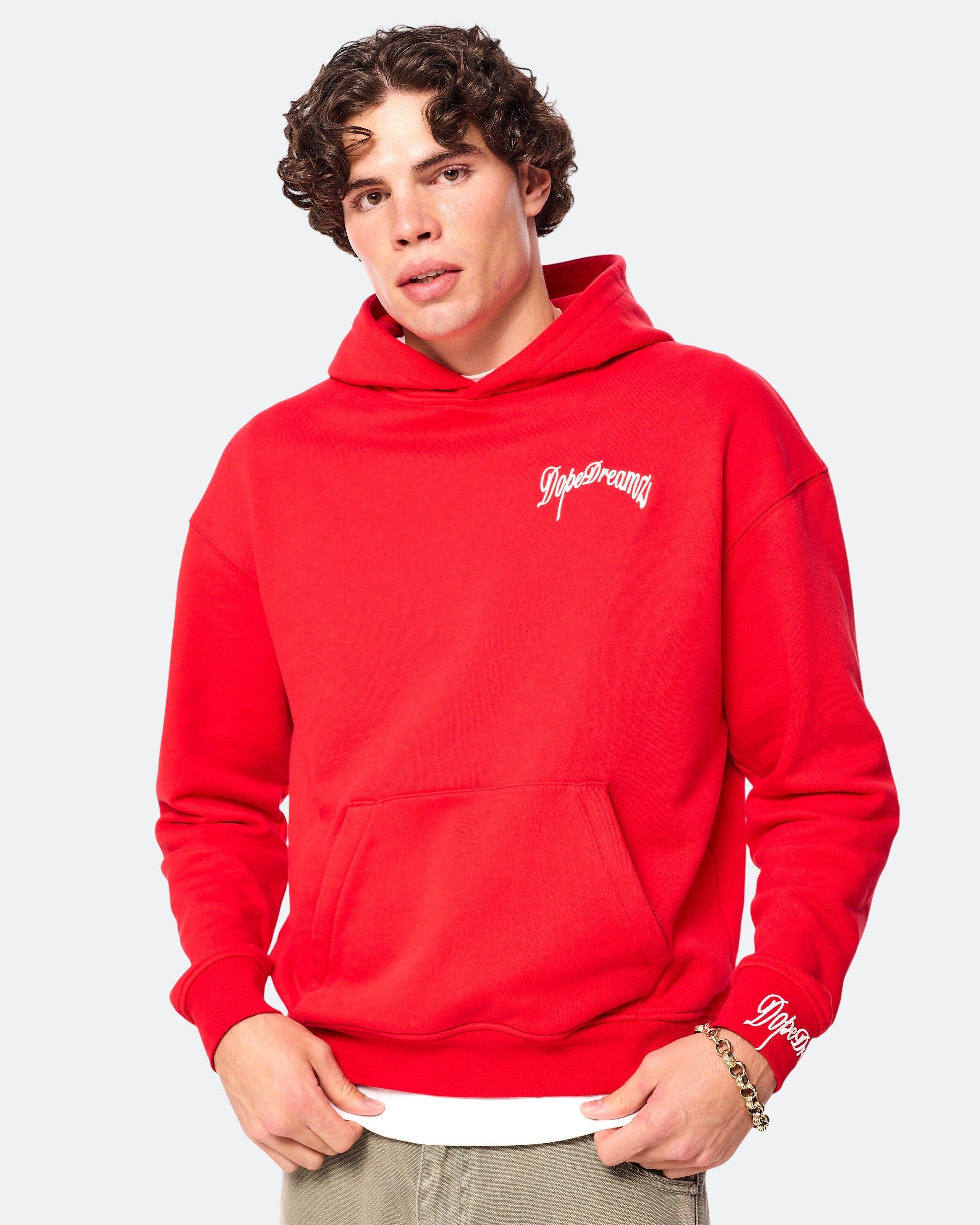 Model wearing red DopeDreamz hoodie with white embroidered chest logo, front view on white background
