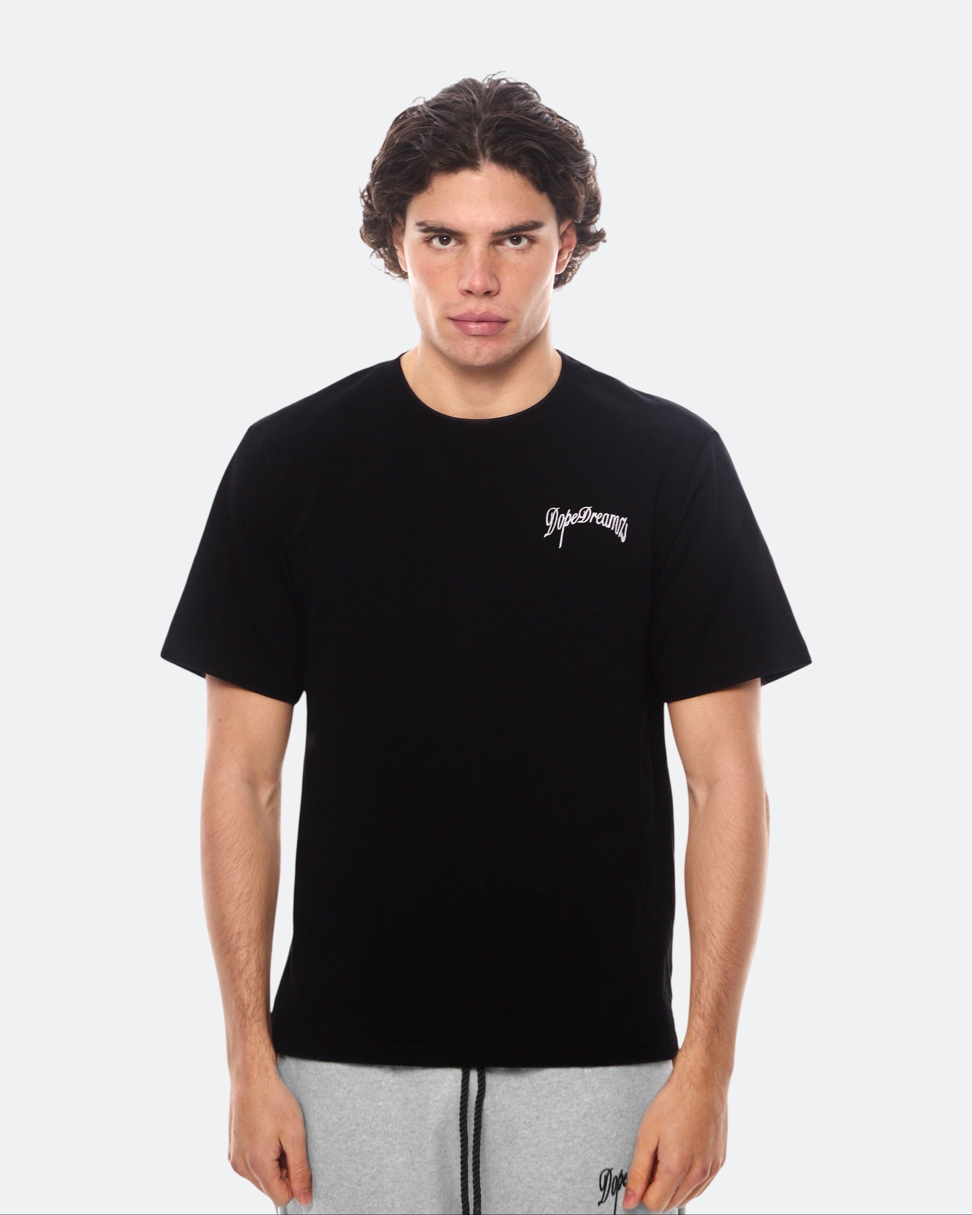 Model wearing a black t-shirt with white 3D embroidered logo on the chest against a white background
