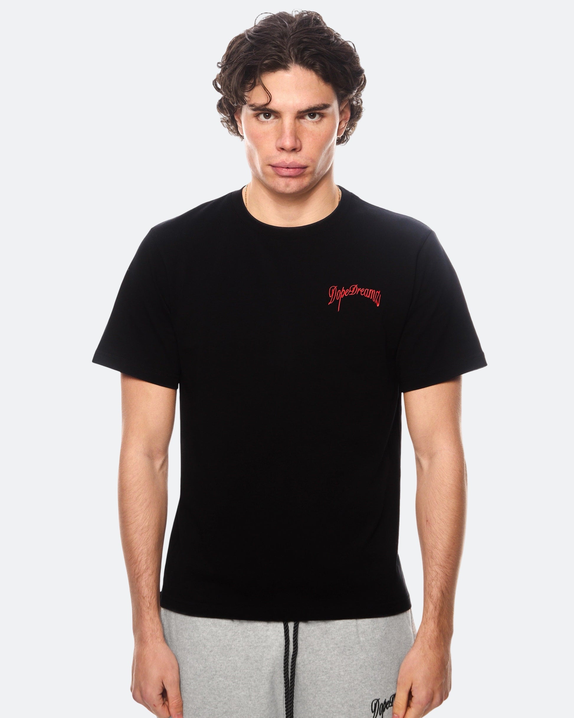Model wearing black DopeDreamz t-shirt with red 3D embroidered chest logo, front view
