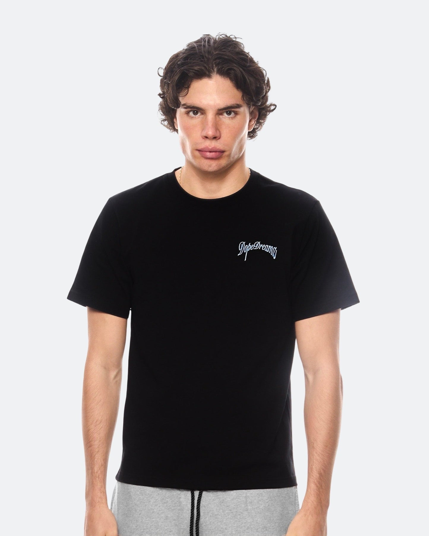Model wearing black DopeDreamz t-shirt with sky blue 3D embroidered chest logo, front view
