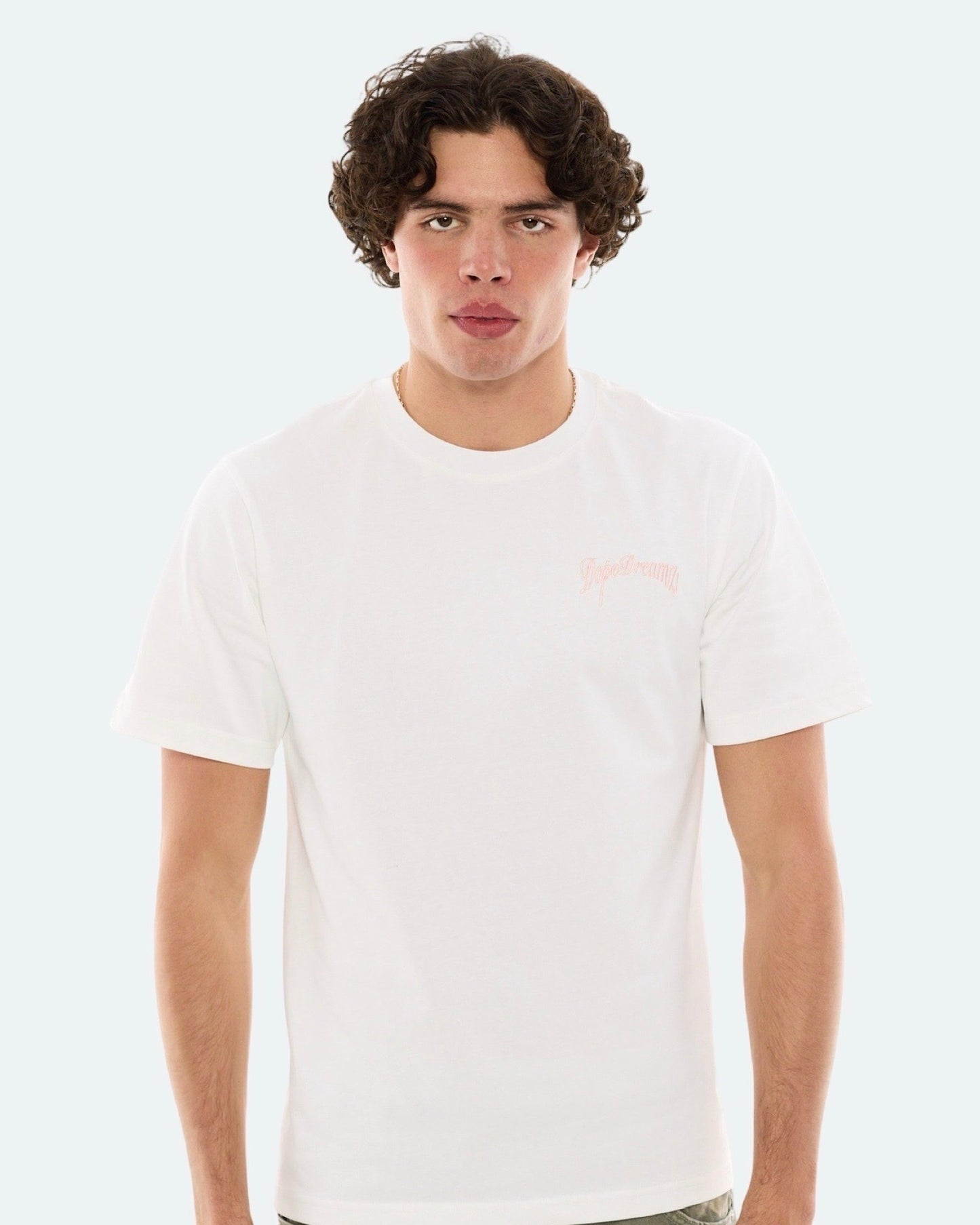 Model wearing white DopeDreamz t-shirt with baby pink 3D embroidered chest logo, front view
