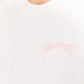 Close-up of baby pink 3D embroidered DopeDreamz logo on white t-shirt
